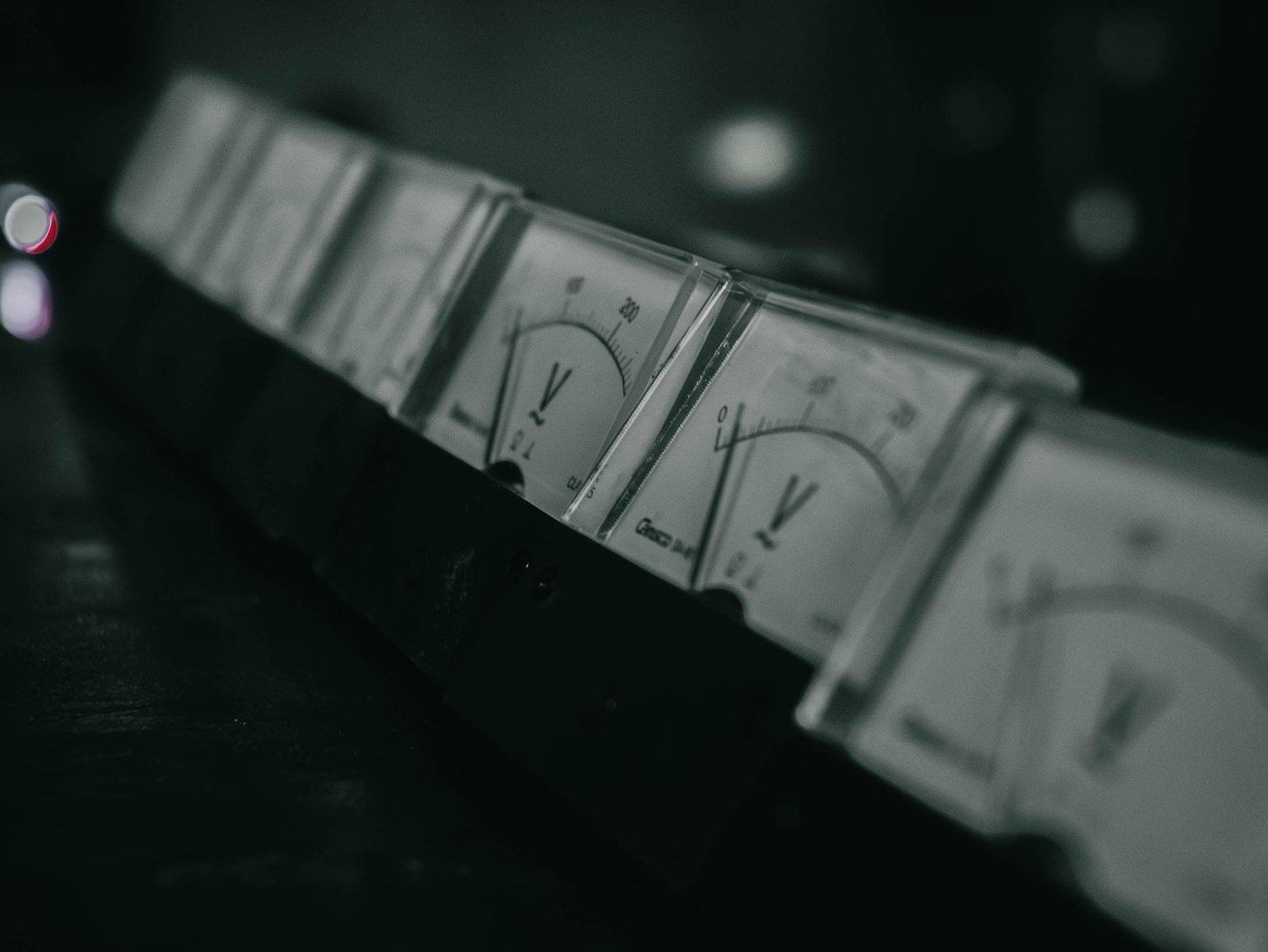 Rivi analogisia sähkömittareita hämärässä